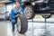 Mechanic Pressing Gauge Into Tire Tread In Garage