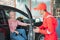 The mechanic in red uniform opens the car door when the customer comes to the car to be repaired