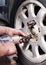 A mechanic at a service station replaces a car wheel, a worker`s hands in black fuel oil and a tool for unscrewing bolts close-up