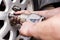 A mechanic at a service station replaces a car wheel, a worker`s hands in black fuel oil and a tool for unscrewing bolts close-up