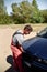 Mechanic standing in front of the open hood and repairing the car