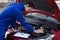 Mechanic in uniform repairing car