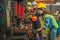 Mechanic workers working with drilling machine in metalwork workshop