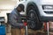 A mechanic working on a lifted up car - Changing wheels using an electric wrench