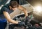 Mechanic working under car hood in repair garage