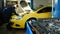 Mechanic works in professional auto service near repairs yellow car, time-lapse