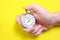 Mechanical stopwatch in a man`s hand on a yellow background