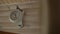 Mechanical white clock hangs in wooden room, time goes on dial