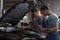 Mechanics with laptop doing car diagnostic at repair shop