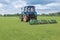 The mechanized hairstyle of a green lawn. Lawn-mower in the field. The mowed grass flies from under a mower knife