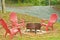 Medal fire pit on bricks with three Adirondack, red, wood, chairs on a drizzly, damp, chilly morning