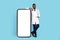 Medical Advertisement. Handsome Black Doctor In Uniform Standing Near Big Blank Smartphone