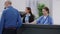 Medical assistant giving support to old patient at reception desk