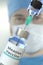 Medical bottle with measles vaccine and syringe against blurred doctor`s face, 3D rendering