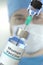 Medical bottle with mumps vaccine and syringe against blurred doctor`s face, 3D rendering