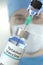 Medical bottle with tetanus vaccine and syringe against blurred doctor`s face, 3D rendering