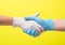 Medical collaboration and doctors hold hands to each other on a yellow background