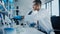 Medical Development Laboratory: Caucasian Male Scientist Looking Under Microscope, Moves Petri Dis