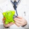 Medical doctor holding stethoscope and piggybank in hand - close up