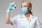 Medical doctor nurse woman wearing protective mask and gloves - holding virus blood test