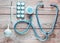 Medical equipment of the therapist on a wooden table: stethoscope, enema, thermometer, tablets, bandage. Top view.