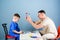 Medical examination. Medical service. Man doctor sit table medical tools examining little boy patient. Pediatrician