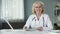 Medical expert reviewing patients test results on tablet sitting in cozy cabinet