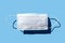 Medical face mask on blue background, hard dark shadow. Levitation of surgical respirator protection against virus, pollution,