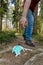 Medical face mask littering in nature.Unrecognizable man bends down to pick up a mask on the ground on a footpath in the forest.