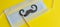 Medical face mask, paper black mustache on a stick on bright yellow background, close-up. Celebrating April Fools ` Day during th