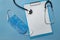 Medical face mask, stethoscope and blank document on blue background. Copy space. Mock up