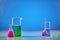 Medical flasks and two beakers, colorful chemical reagents for tests, blue background. Laboratory research of