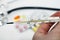 Medical glass thermometer with high temperature in hands on the background of various drugs, vitamins, antibiotics and tablets