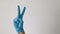 Medical hand with blue glove doing the V gesture