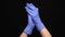 Medical hands with blue gloves clapping on black background