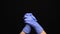 Medical hands with blue gloves clapping on black background