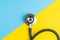 Medical, health care or illness and disease diagnose concept, flat lay of doctor`s stethoscope on contrast color yellow and blue.