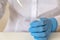 A medical lab worker in blue sterile gloves pours liquid into a small test tube