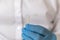 A medical lab worker in blue sterile gloves pours liquid into a small test tube.