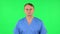 Medical man carefully looks at the camera in frustration. Green screen