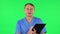 Medical man thinks, speaks and writes at black folder with pensil. Green screen