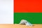 A medical mask lies on the table against the background of the flag of Madagascar.