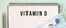 A medical mask and a thermometer are on the notepad. VITAMIN D text in a notebook