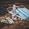 Medical masks, pills, antiseptic in a transparent plastic bottle and black rubber gloves on a wooden background. Covid-19 virus