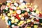 Medical pills on teaspoon and heap of colorful medical capsules in background, health care concept