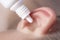 Medical pipette with a drop of medication over the patient`s ear