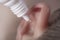 Medical pipette with a drop of medication over the patient`s ear