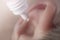 Medical pipette with a drop of medication over the patient`s ear