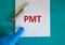 Medical and PMT, premenstrual tension symbol. Pen. White note with the word `PMT`. Beautiful blue background. Doctor hand in blu