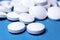 Medical round white tablets, calcium vitamins closeup on blue background with space for text or image. Pills